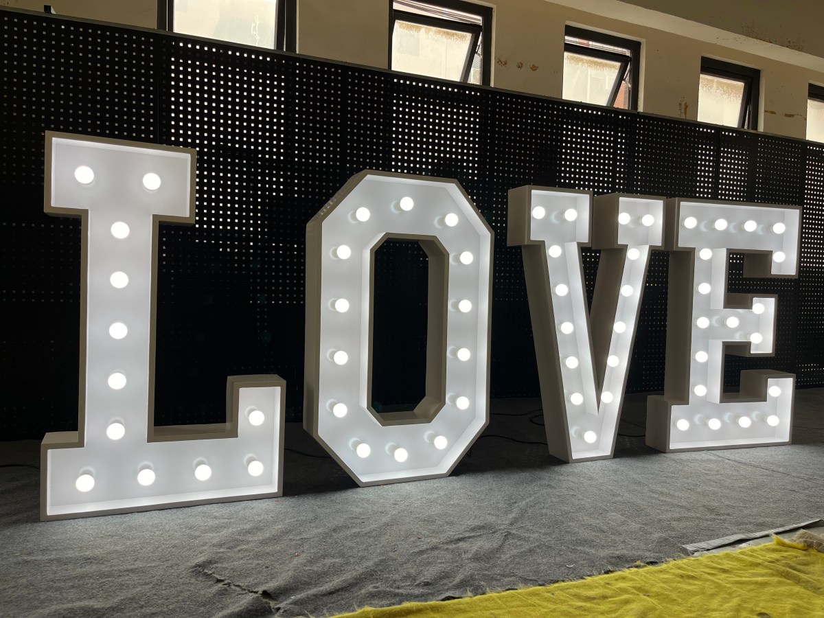 White marquee letters spelling LOVE, lit and standing on the workshop floor