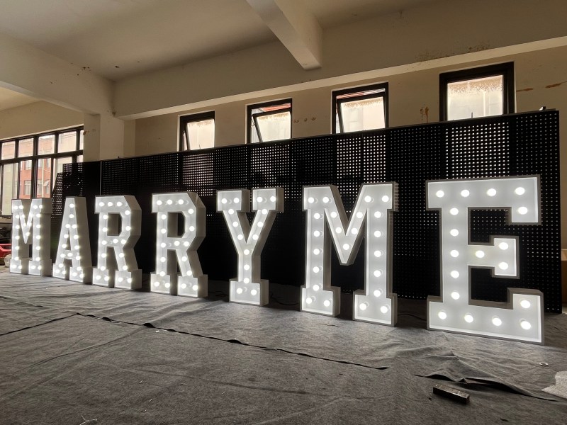 Marquee letters spelling MARRY ME, lit in warm-white bulbs