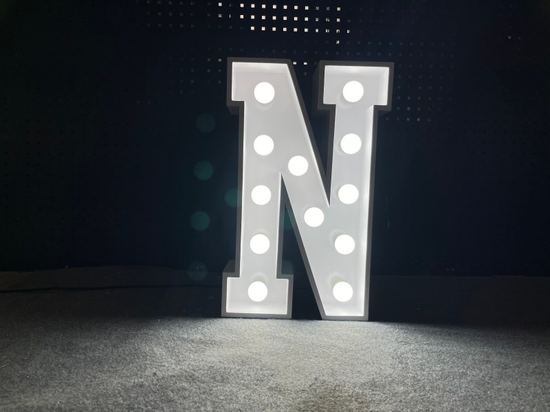 A single marquee letter N lit at night, showing the bulb sockets across the punched face