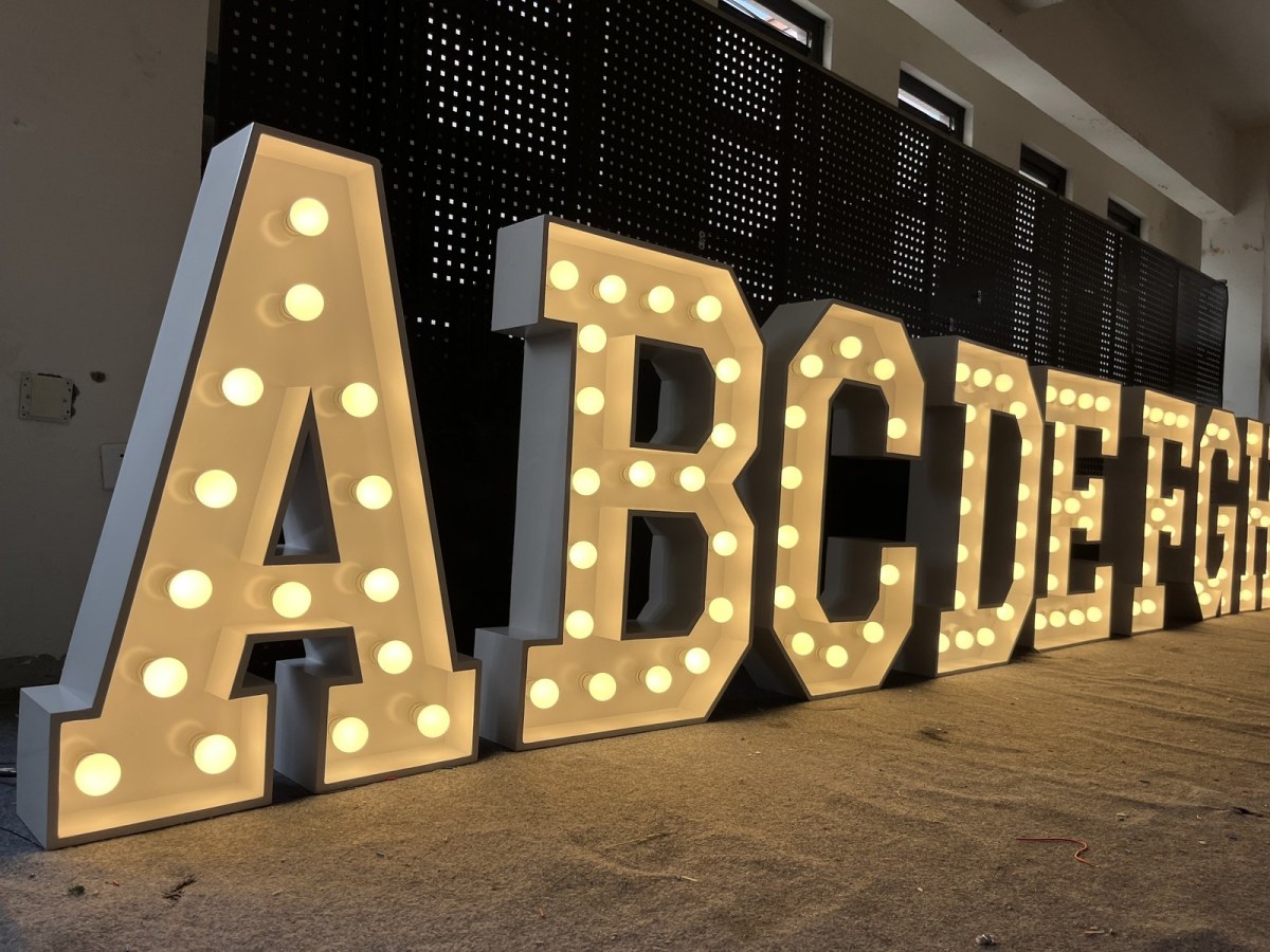 A full run of illuminated marquee letters, A through H, standing on the workshop floor