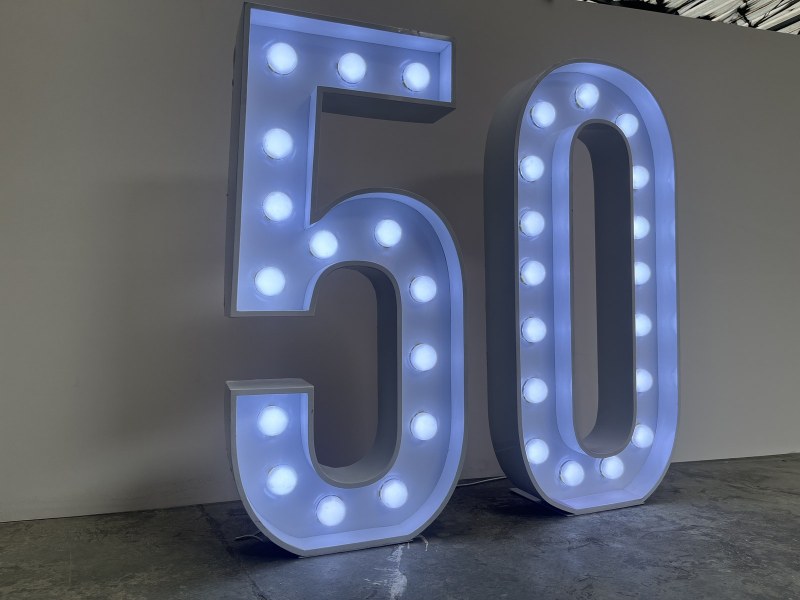 Two 4ft marquee characters, a 5 and a 0, lit in warm white against a plain wall